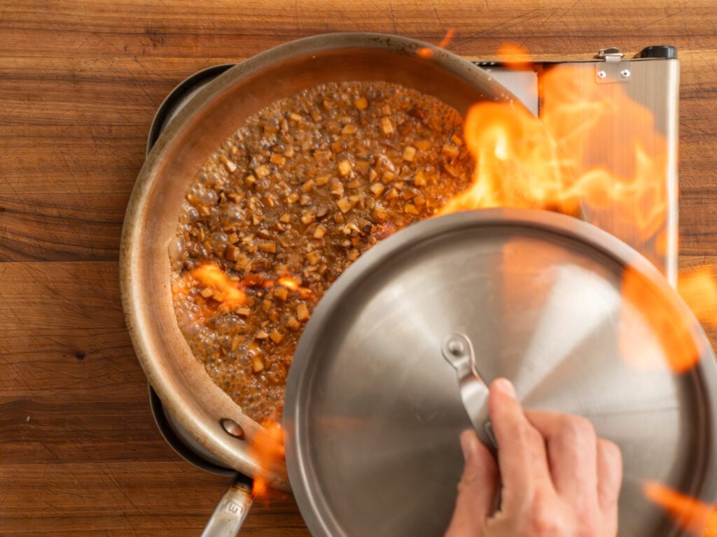 flambeeing steak diane sauce in saute pan
