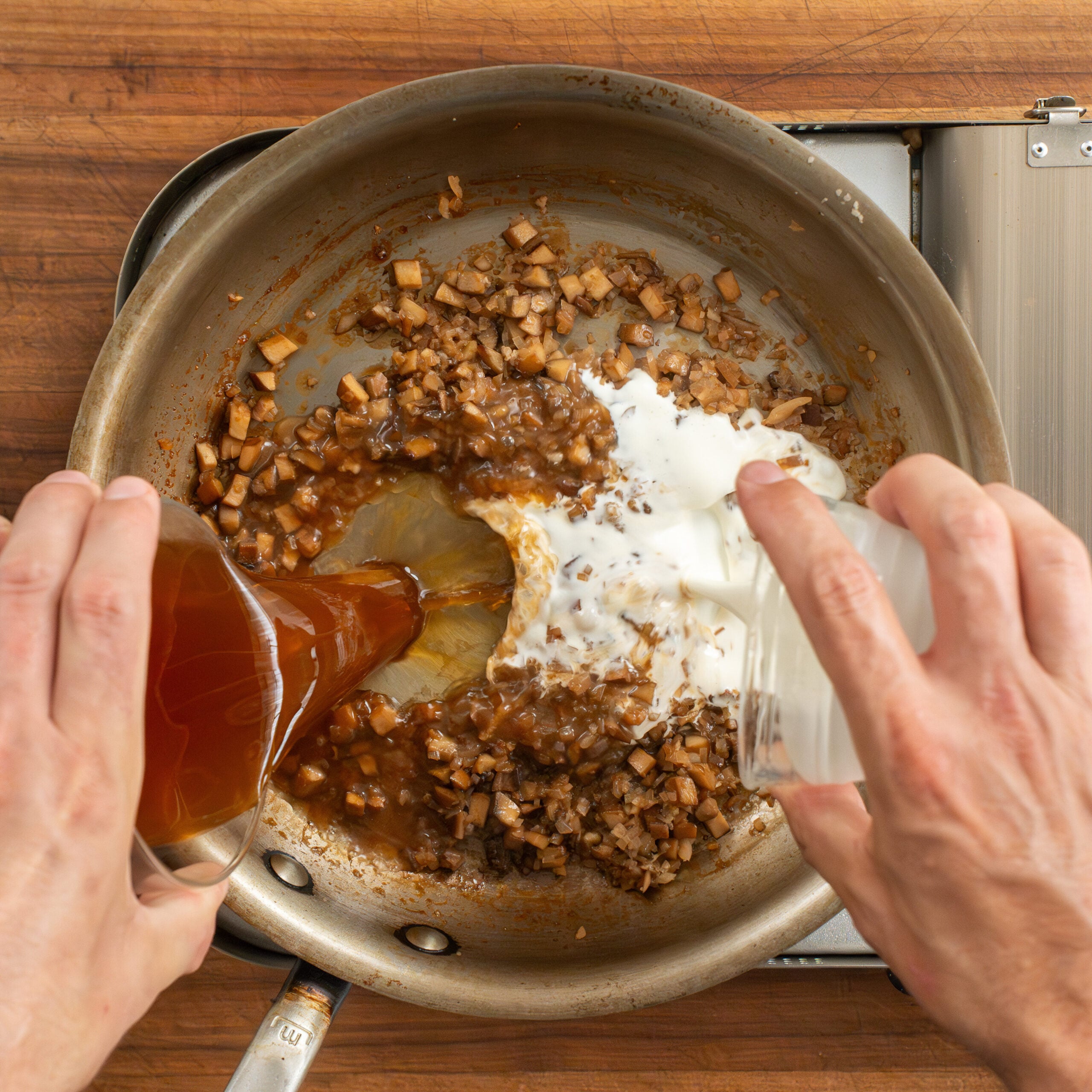 adding cream and beef stock to mushroom pan sauce