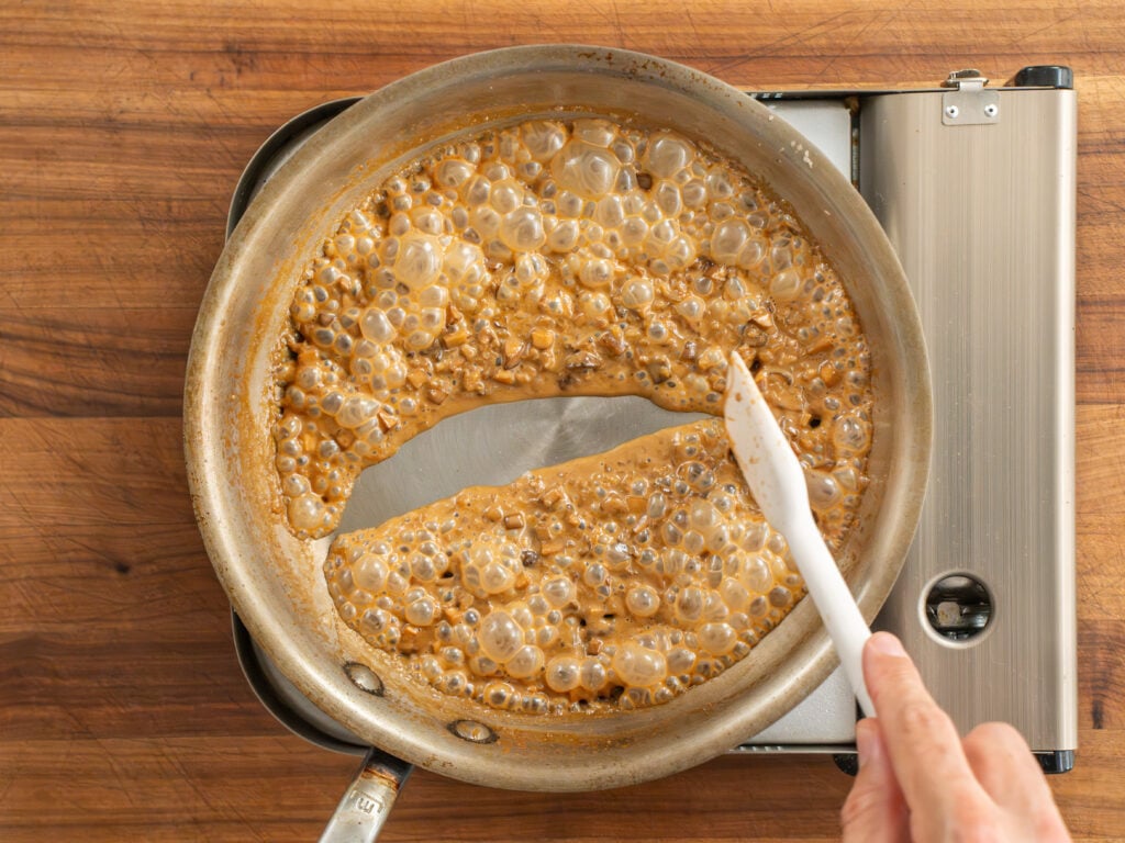 passing white spatula through bubbling steak diane sauce