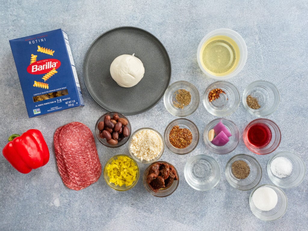ingredients for Italian pasta salad arranged on grey background
