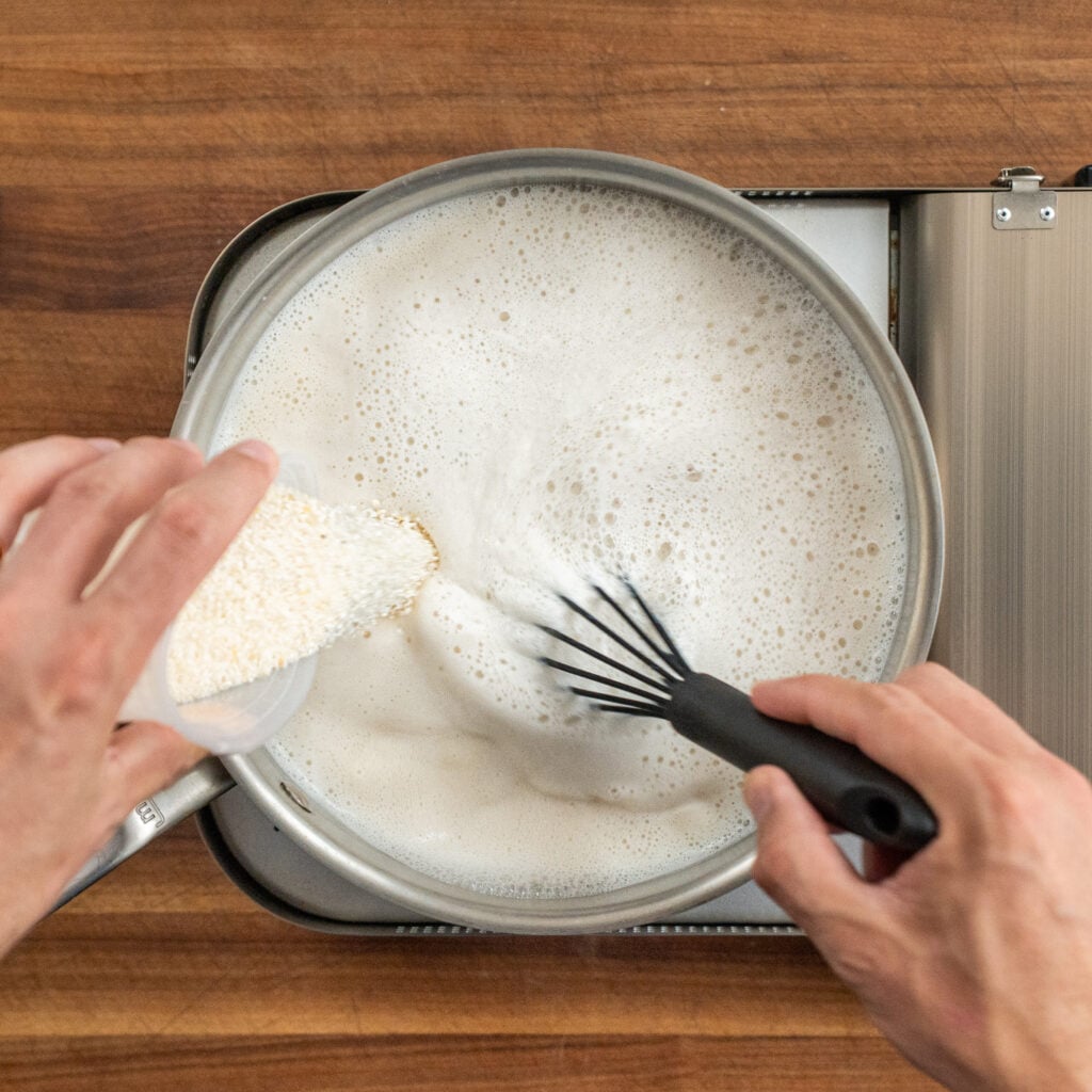 adding grits into sauce pan of milk and chicken stock