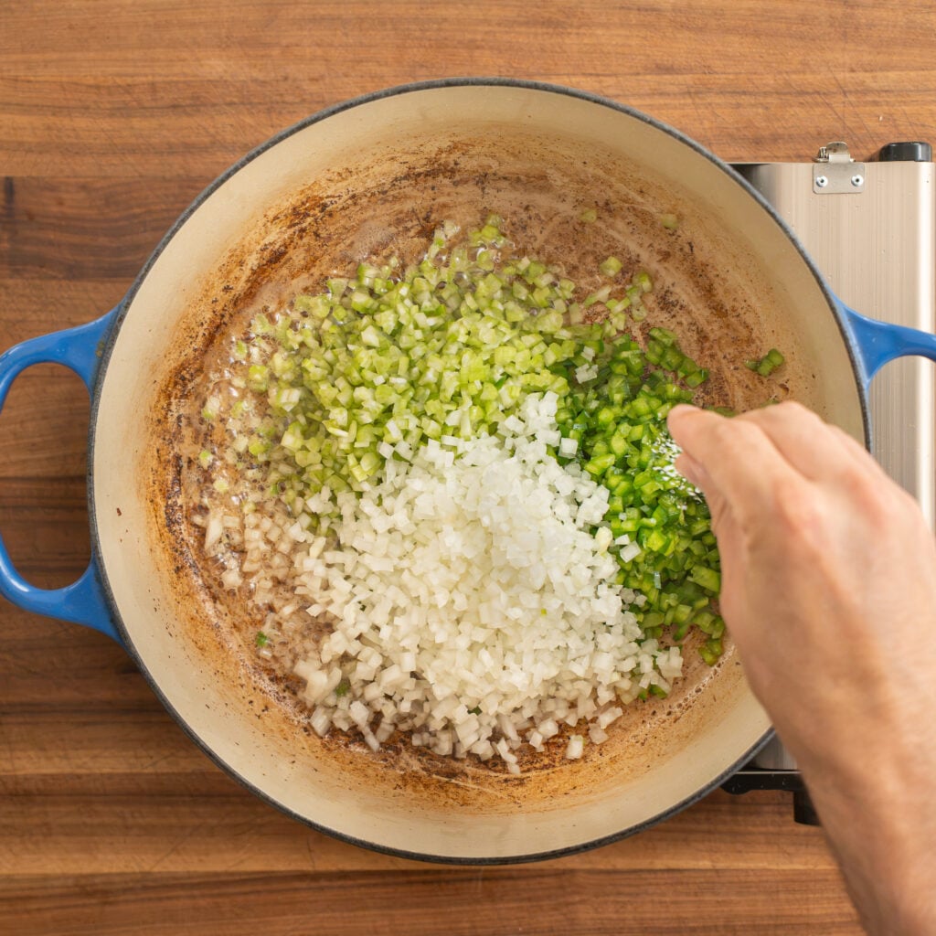 separate piles of onion celery and bell pepper in dutch oven