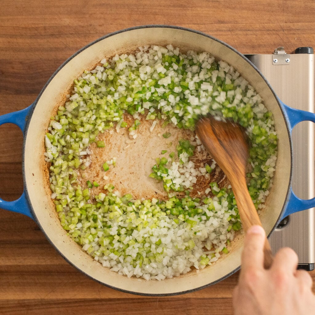 wooden spoon stirring diced onion and celery