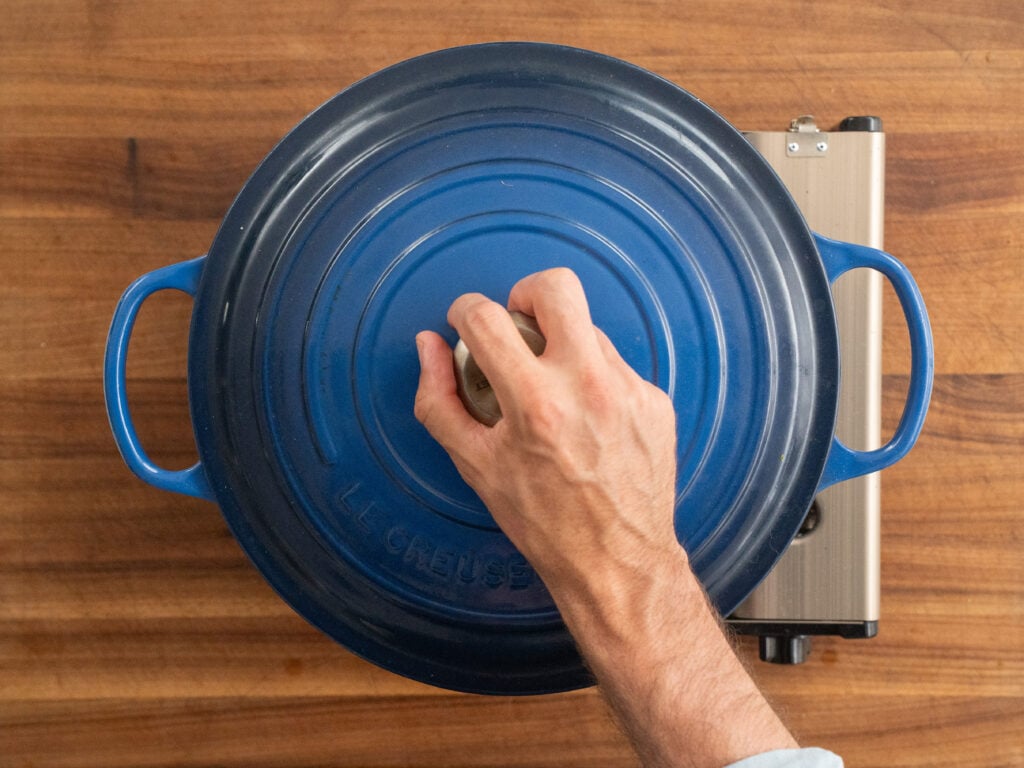 man holding handle of blue dutch oven lid