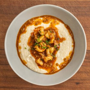 grey bowl filled with grits topped with shrimp gravy