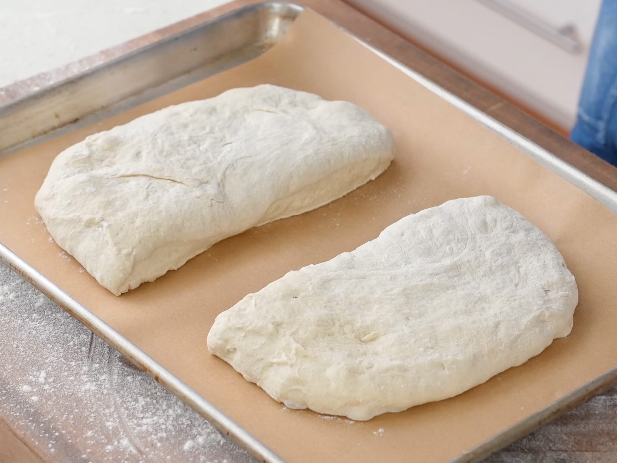 two halves of bread dough on parchment lined sheet tray