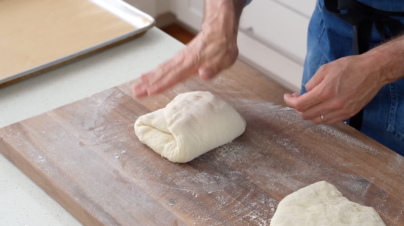 hand patting bread dough that has been folded into thirds to form rectangle