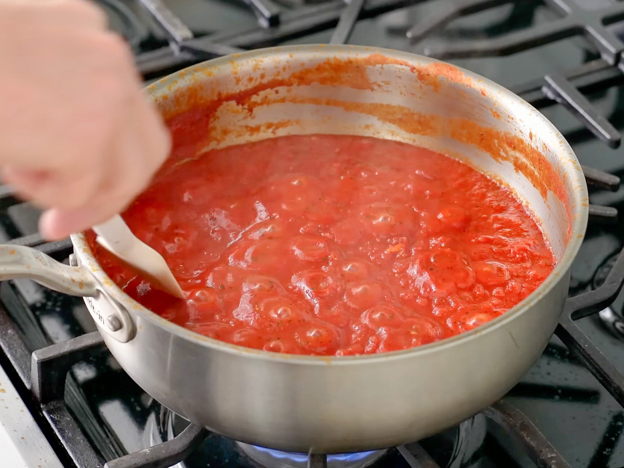 white spatula stirring tomato sauce in silver sauce pan