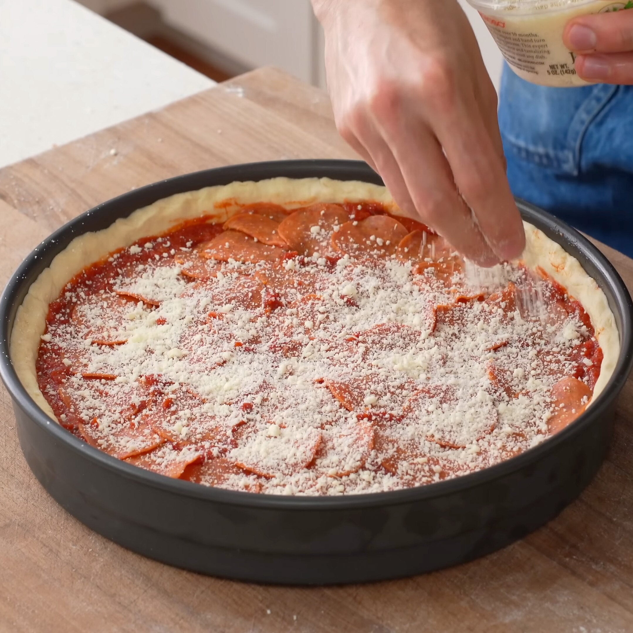 adding parmesan to deep dish pizza