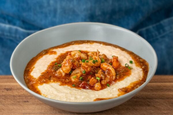 grey bowl of shrimp and grits on wood cutting board