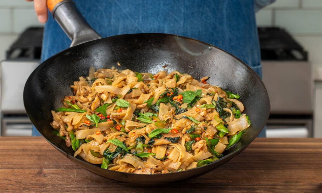 man holding wok of drunken noodles