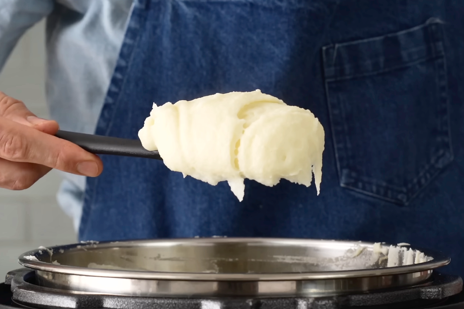 man holds black spoon of potato puree