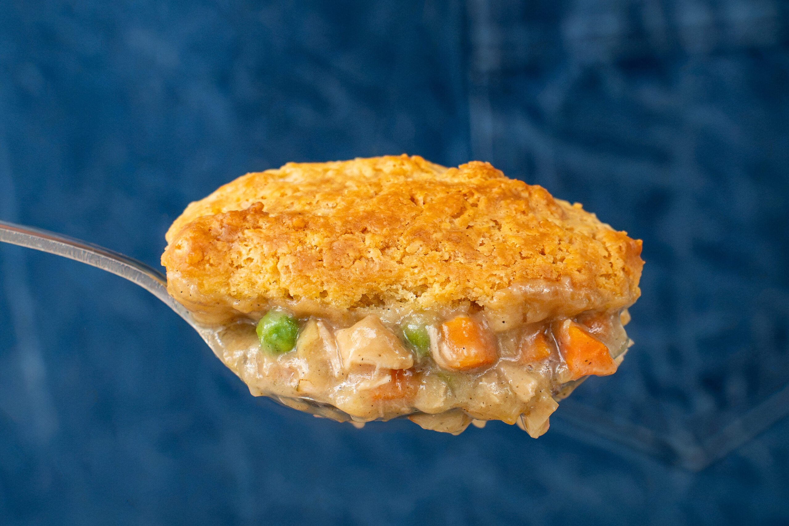 spoon holding a bite of chicken pot pie with drop biscuit
