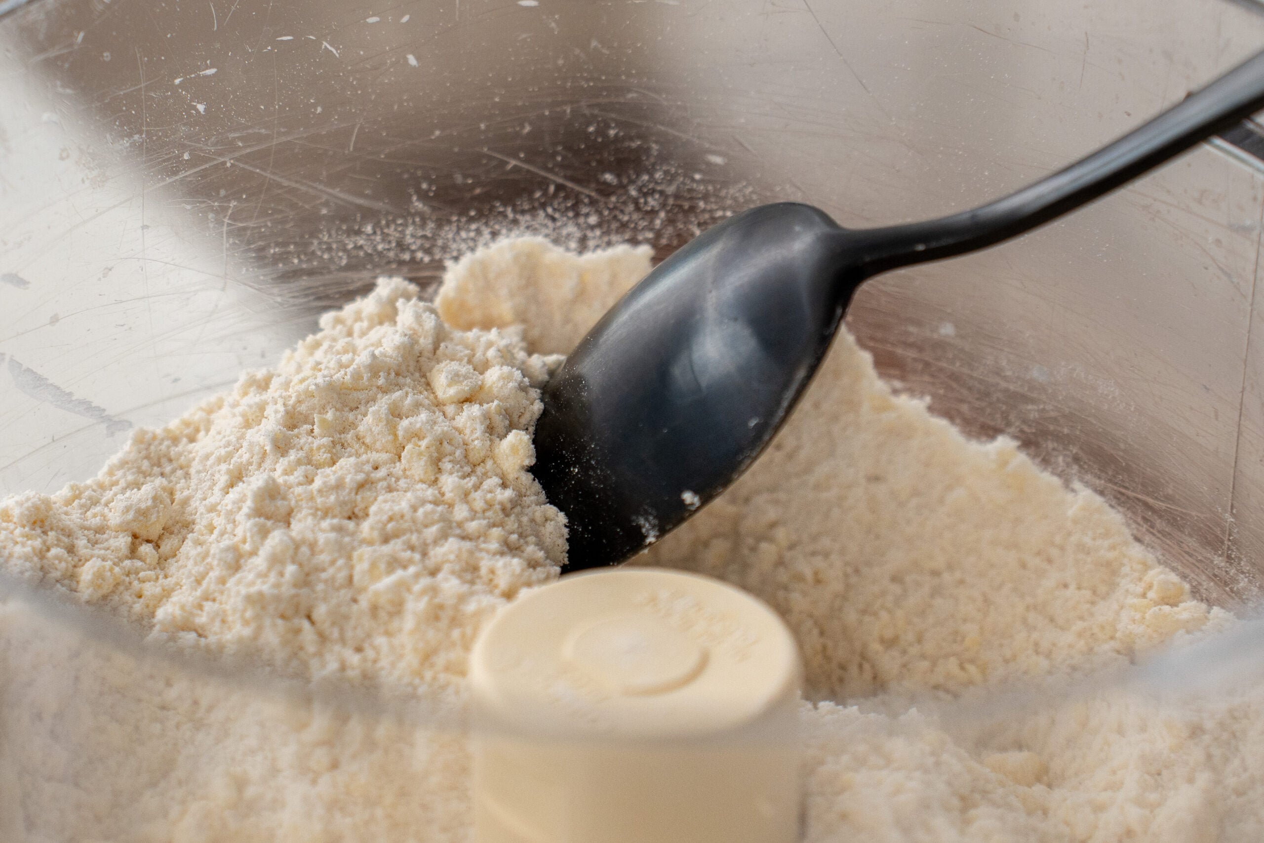 black spoon displaying pebbly texture of mixed dry ingredients in biscuit dough