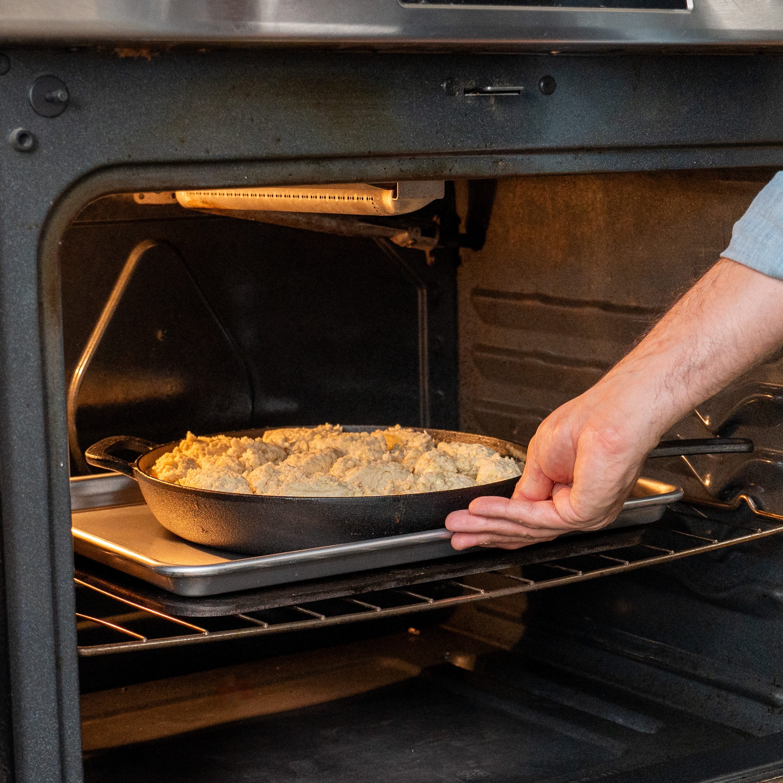 loading cast iron pan filled with chicken pot pie and drop biscuits into oven