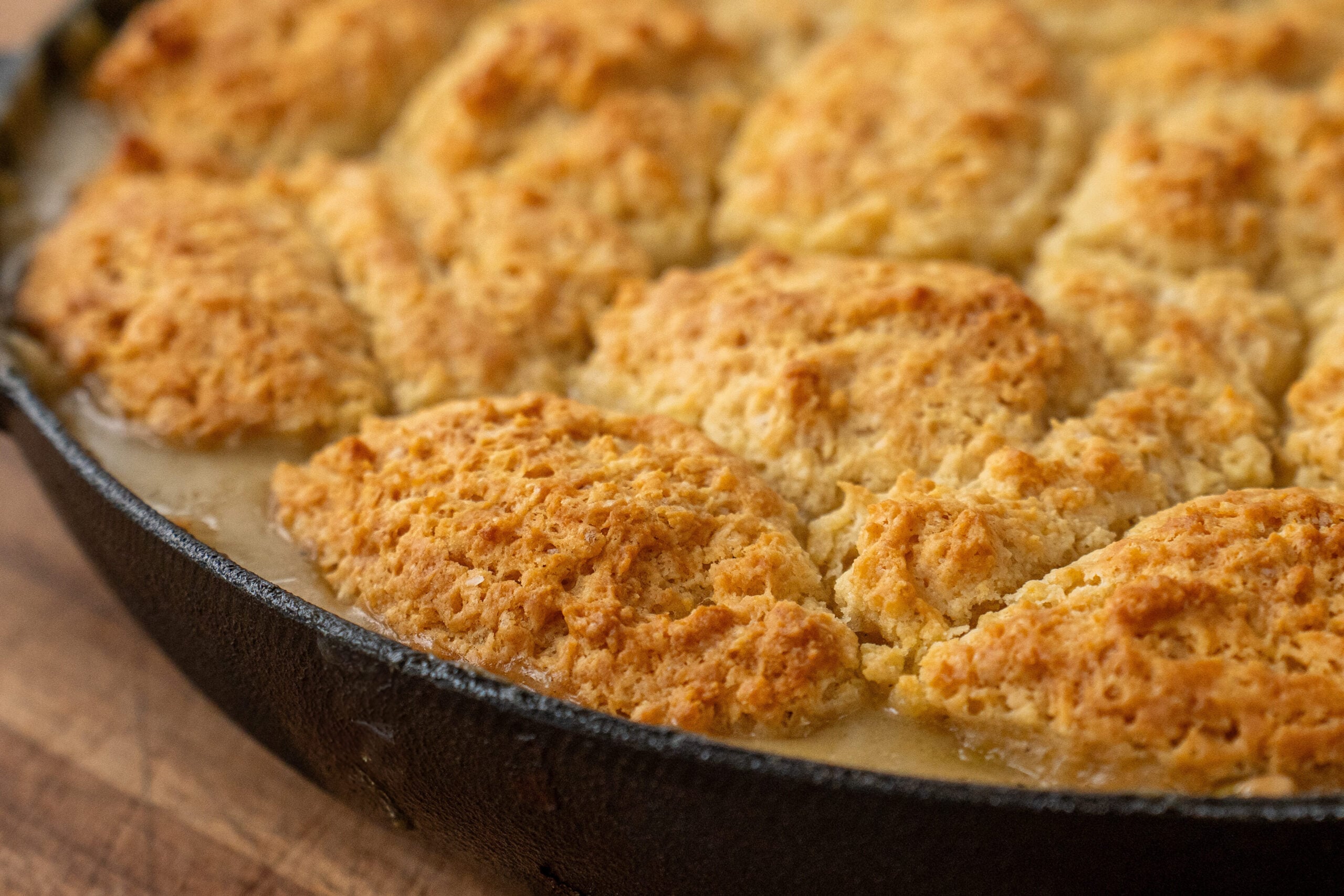 close up of golden brown drop biscuits on top of chicken pot pie filling