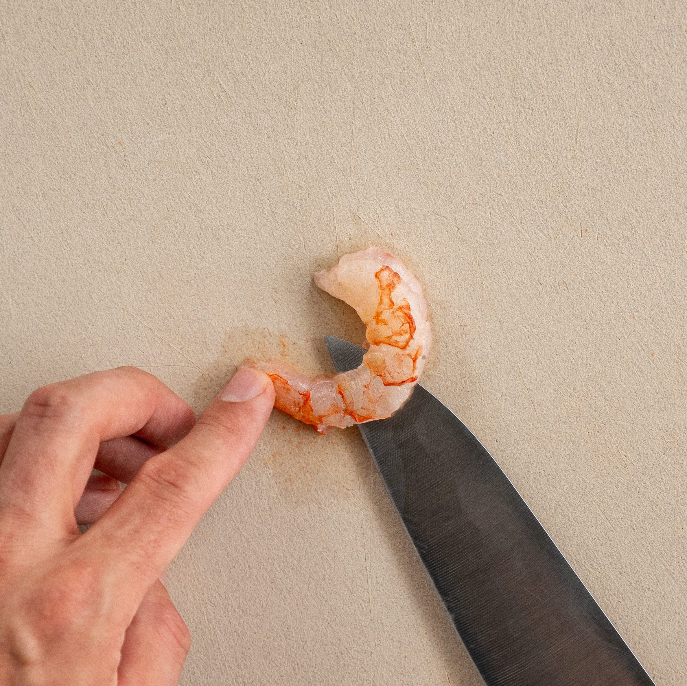 knife slicing through a raw shrimp