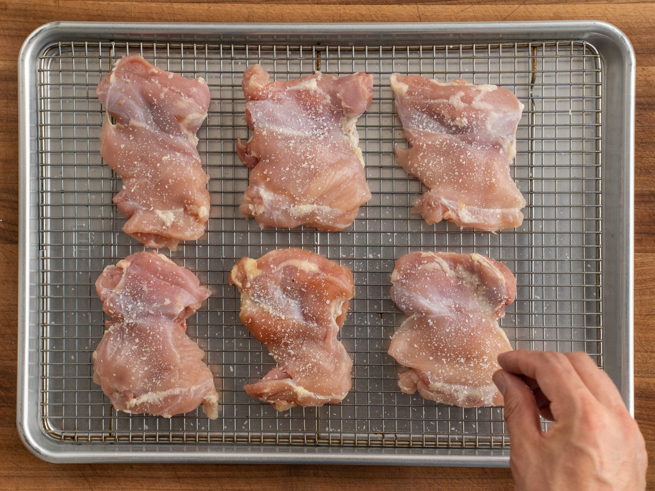 salting raw chicken thighs sitting on wire rack