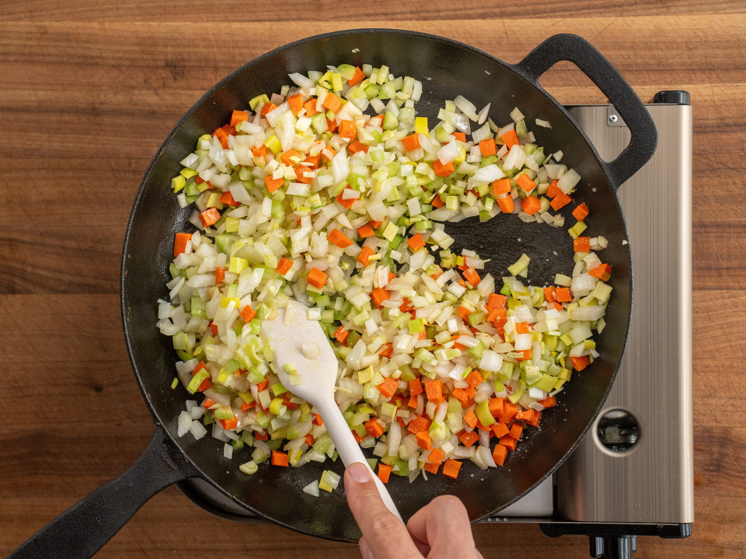 stirring mirepoix in black cast iron pan
