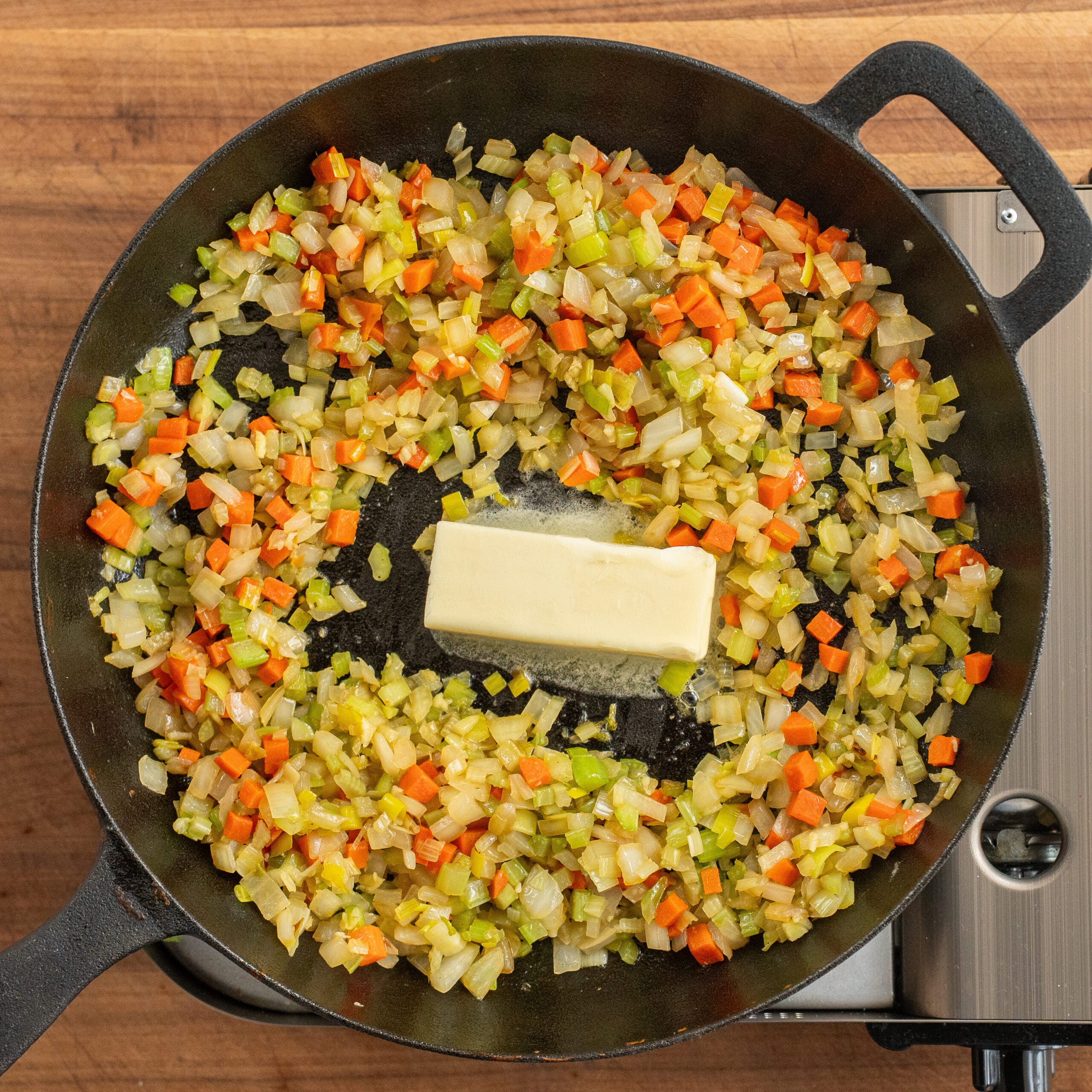 butter melting in to cast iron pan of mirepoix
