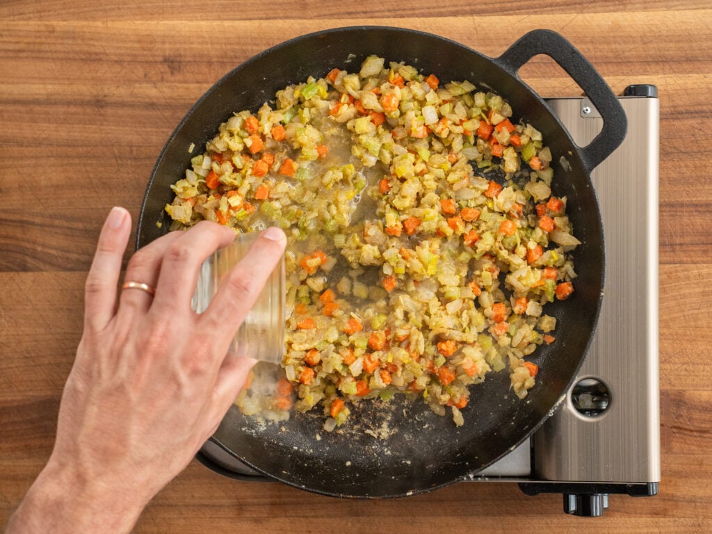 adding white wine to cooking vegetables