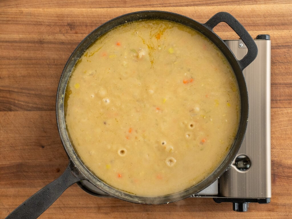 chicken pot pie filling cooking and bubbling in black cast iron pan