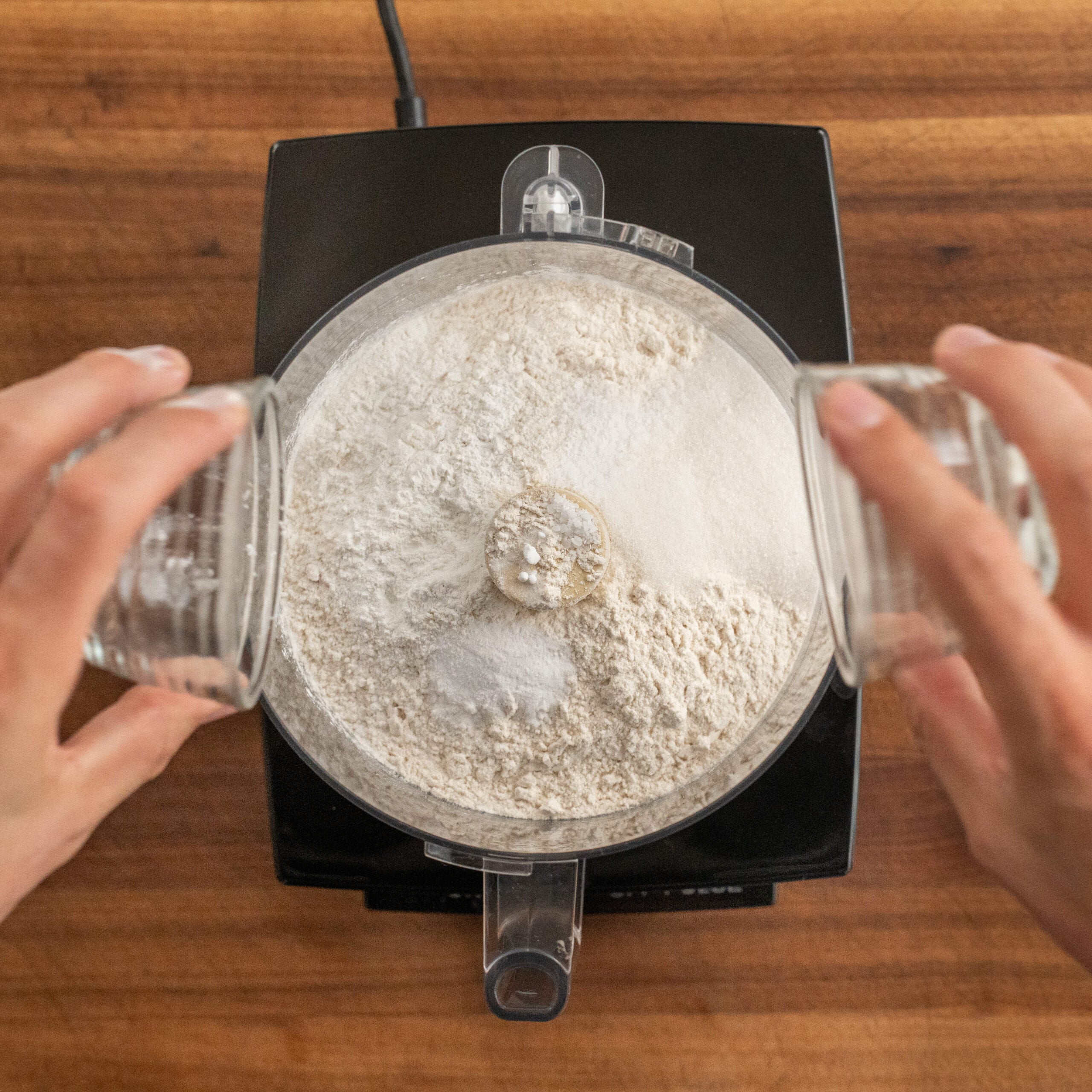 adding dry ingredients into food processor bowl