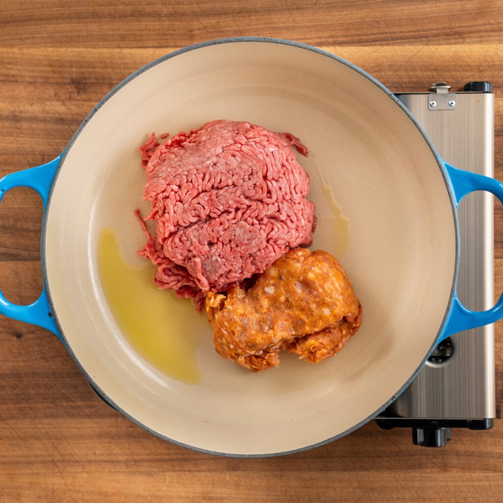 raw ground been and ground pork in blue dutch oven