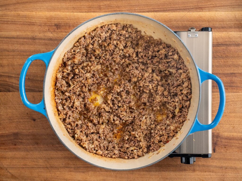 cooked ground beef and onions in blue dutch oven