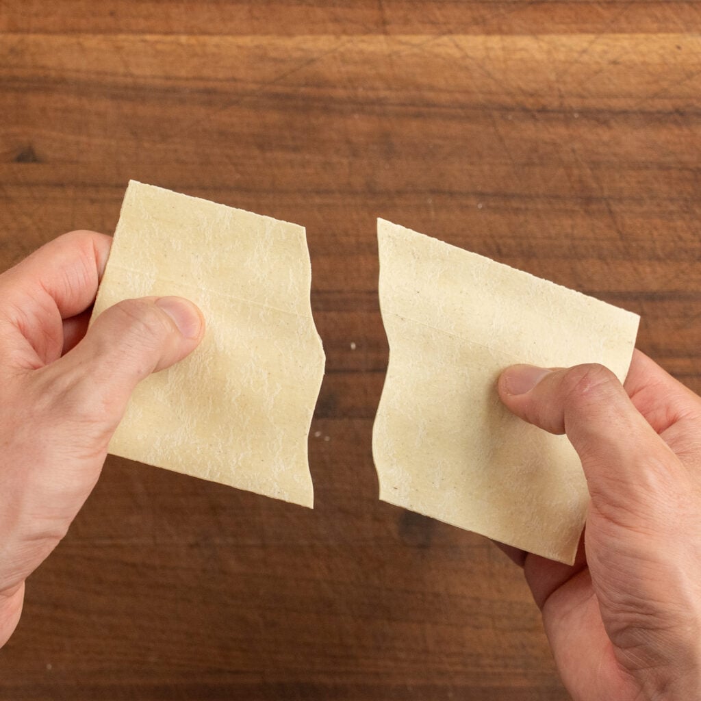 hands breaking dry lasagna sheet in half