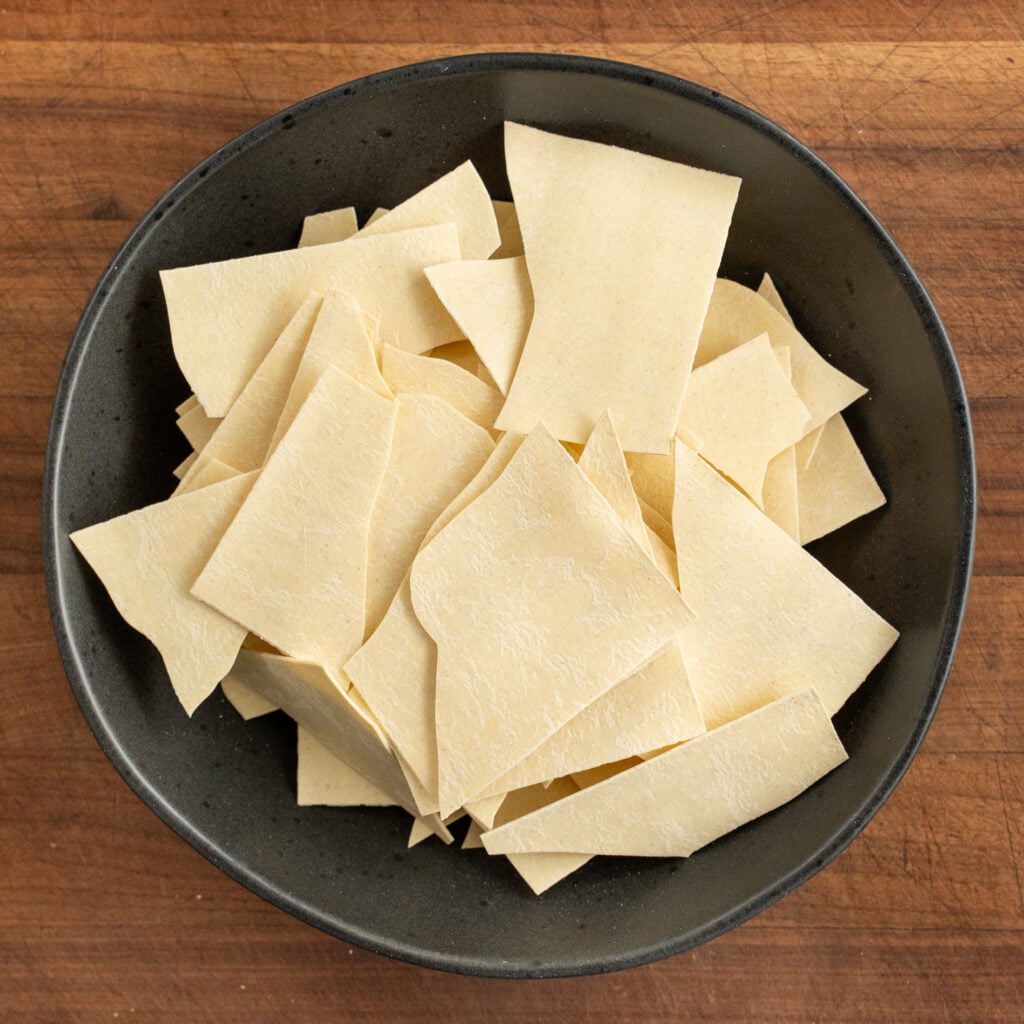 black bowl filled with broken dry lasagna sheets